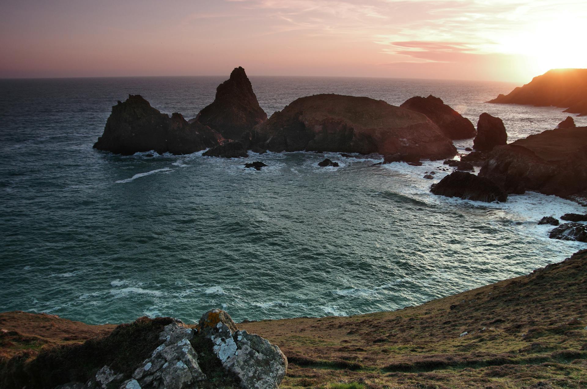 Breathtaking sunset over rocky coastal landscape at Mullion Cove, capturing the essence of Cornish seaside beauty.