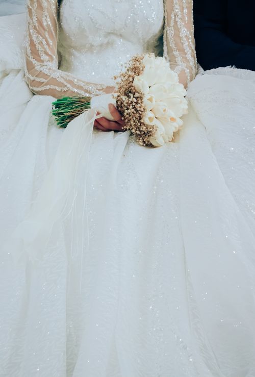 Free Close-up of a bride holding a bouquet, highlighting the intricate details of her wedding gown in İzmir, Turkey. Stock Photo