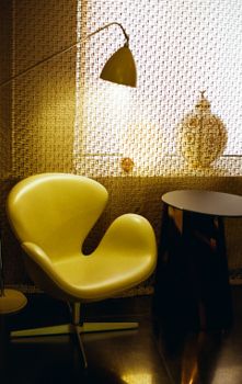Modern interior with a designer chair and lamp casting warm light in a cozy room setting.