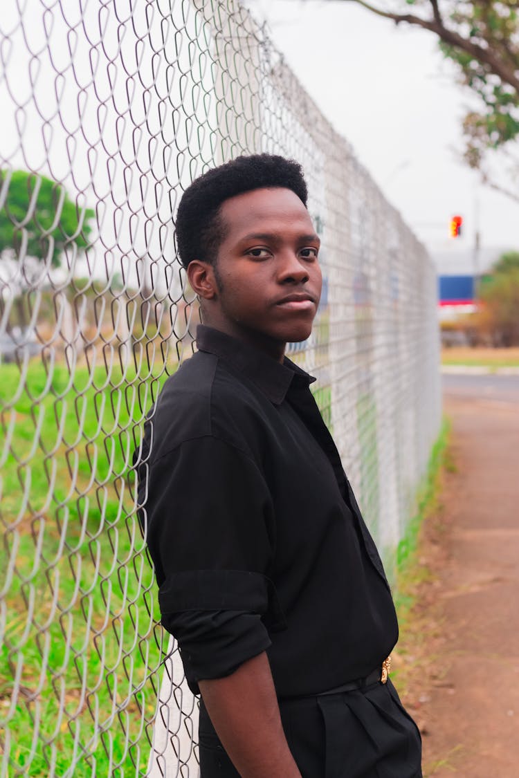 Man Leaning Against Net Fence