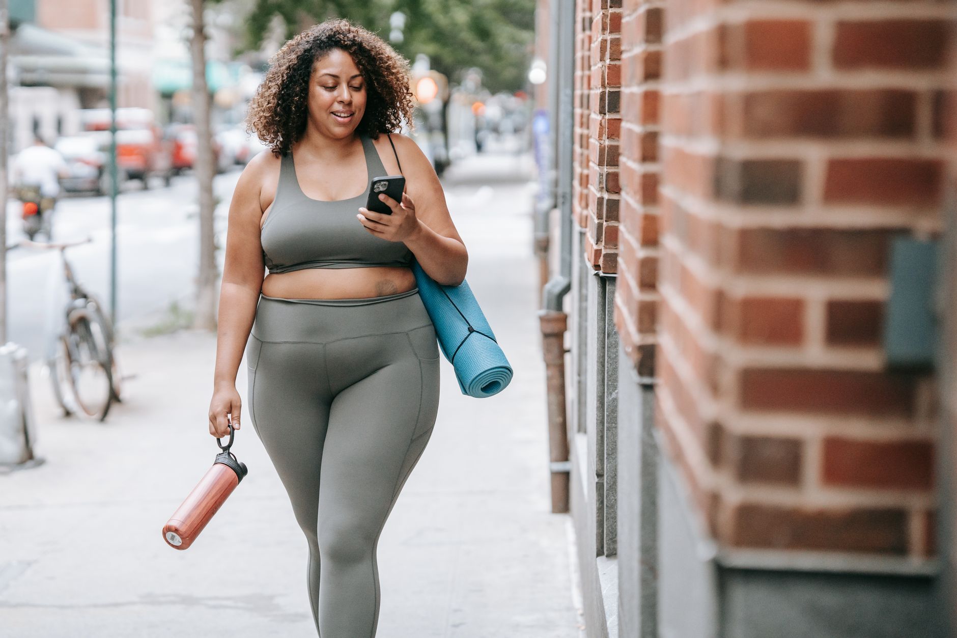 Best Phone Camera Settings for Outdoor Photos (Sharper Colors) Confident woman in sportswear walking outside with yoga mat and phone, embracing positivity