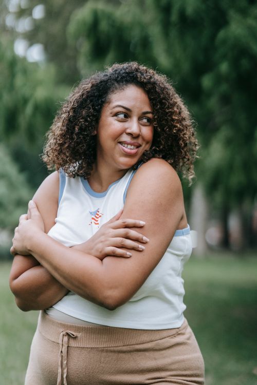 Free A cheerful woman embraces herself outdoors, promoting body positivity and self-love. Stock Photo