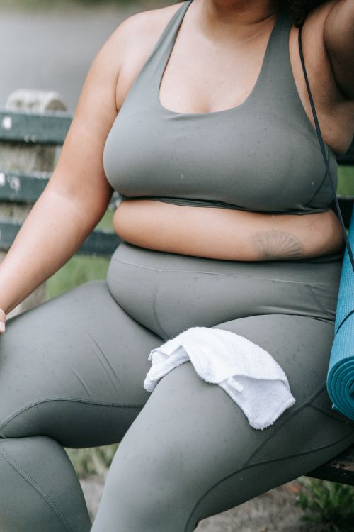 Free Plus-size woman resting with yoga mat and towel in sports attire, embodying confidence. Stock Photo