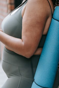 A woman in sportswear holding a yoga mat, representing fitness and healthy living.