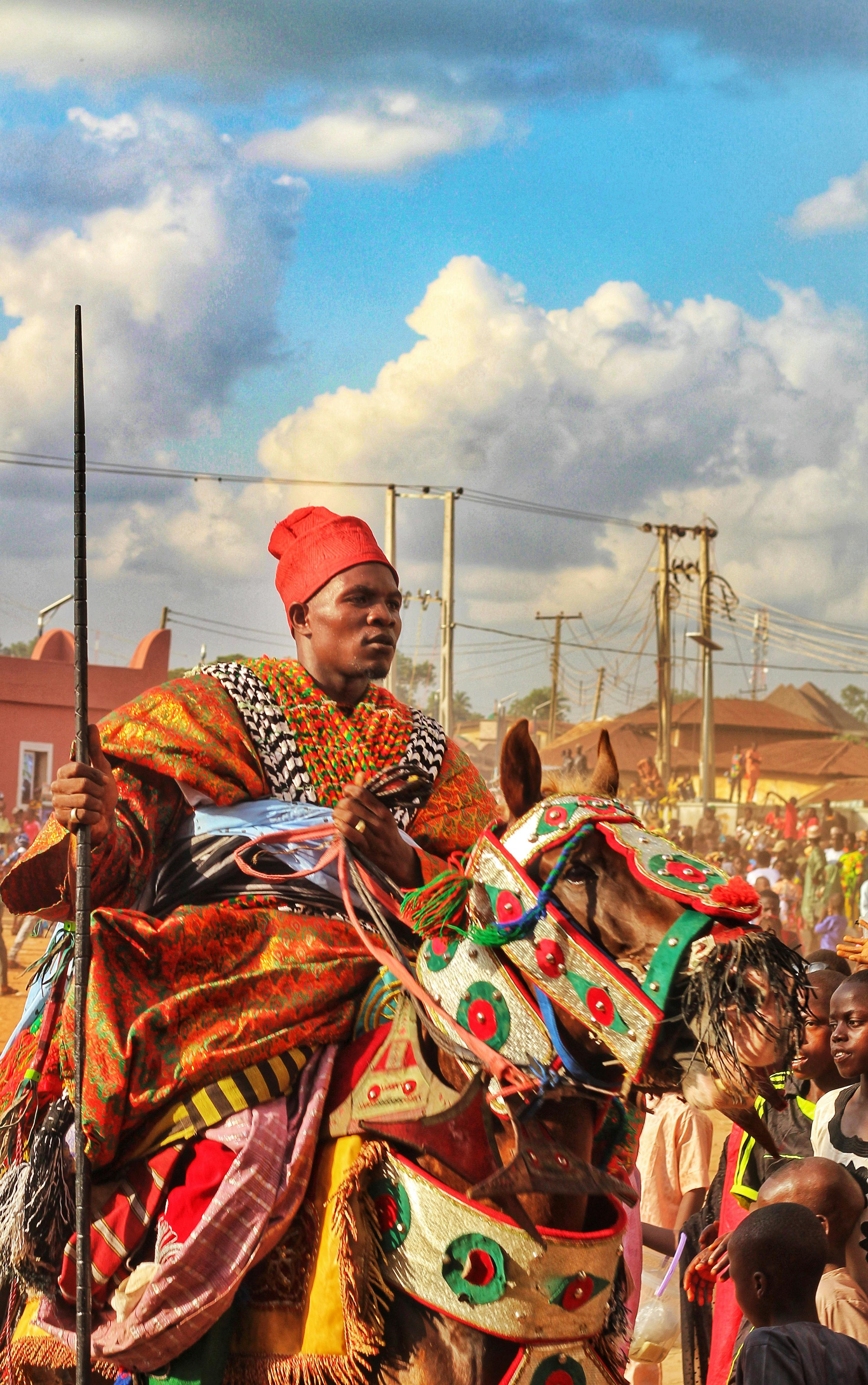 A vibrant cultural parade featuring a traditionally dressed horse rider under a bright sky.