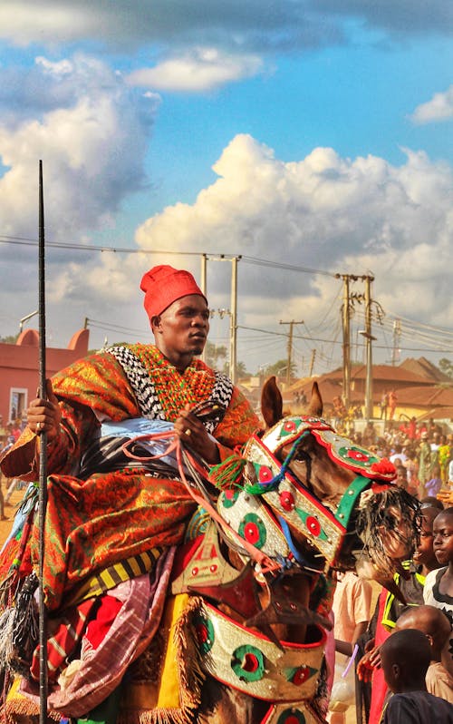 Photo of a Man Dressed in Colorful Traditional Clothes and Riding a Horse