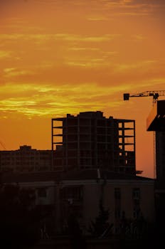 A striking silhouette of buildings against a vibrant orange sunset sky.