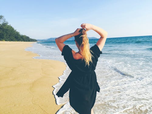 бесплатная Женщина, стоящая на берегу моря Стоковое фото