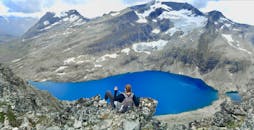 在挪威霍尔，徒步旅行者俯瞰原始湖泊和白雪皑皑的山峰，景色令人惊叹