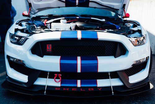 Free Close-up of a Ford Mustang Shelby GT350 with hood open, showcasing its powerful engine at a car show. Stock Photo