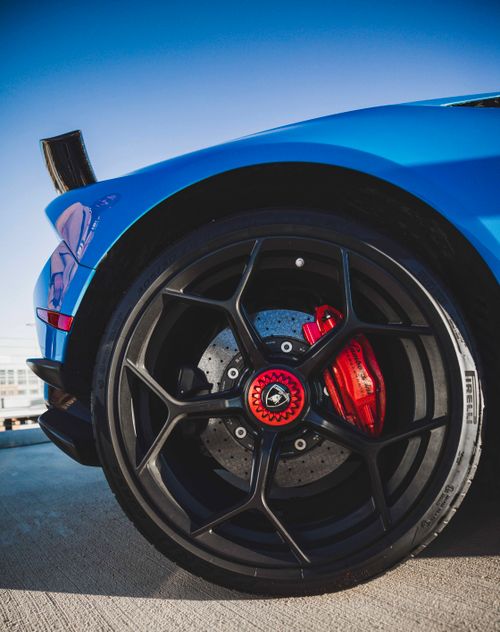 Free A detailed close-up of a blue sports car wheel showcasing sleek design and vibrant color. Stock Photo