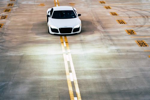 Free Aerial view of a white Audi R8 parked in an empty garage, emphasizing its luxury design. Stock Photo