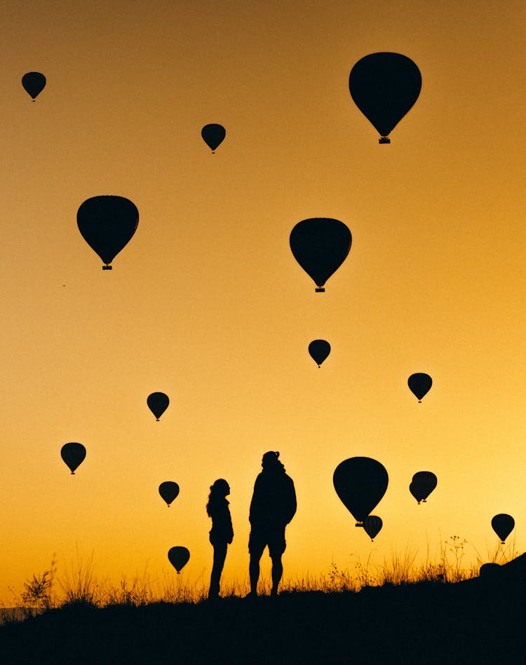 A Couple Watching Balloons At Sunset