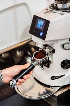 Close-up of a barista using a grinder to prepare fresh espresso grounds.