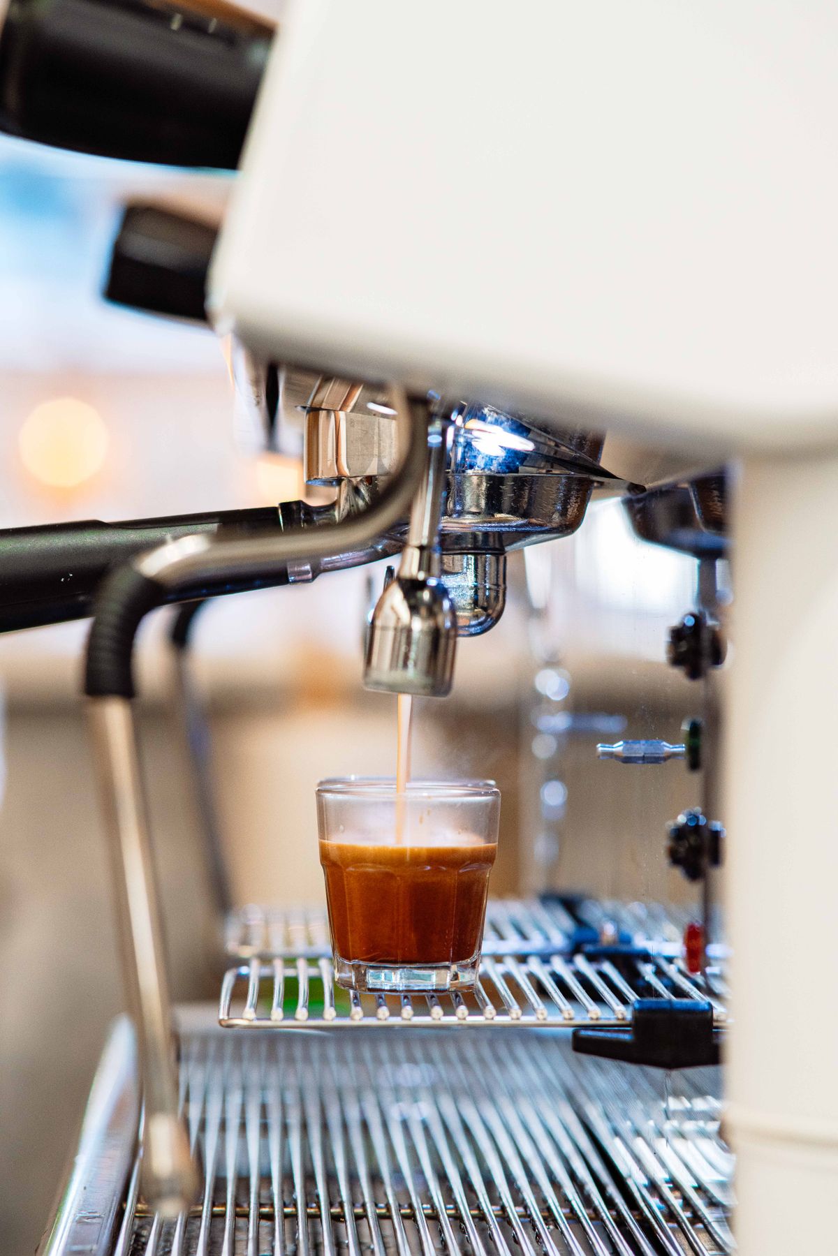Close-up of a commercial espresso machine brewing, for illustration