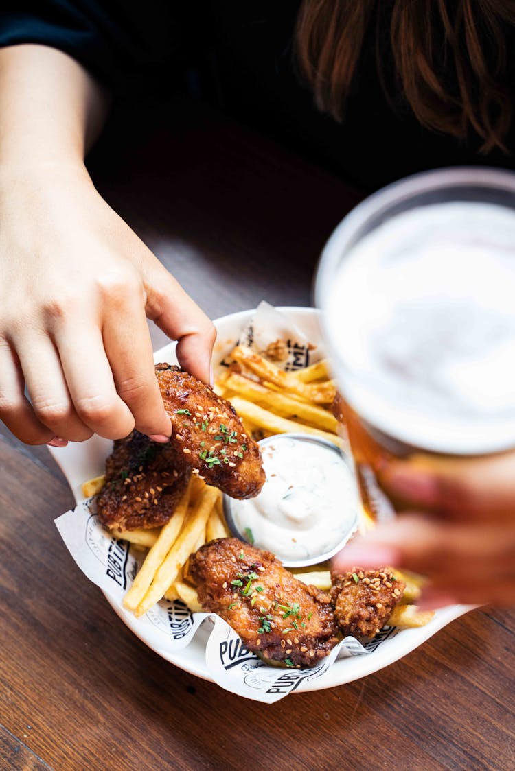 Close Up Of A Girl Eating Chicken Nuggets With French Fries And Sauce