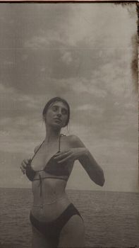 Artistic vintage beach photo of a woman in a bikini with a timeless aesthetic.