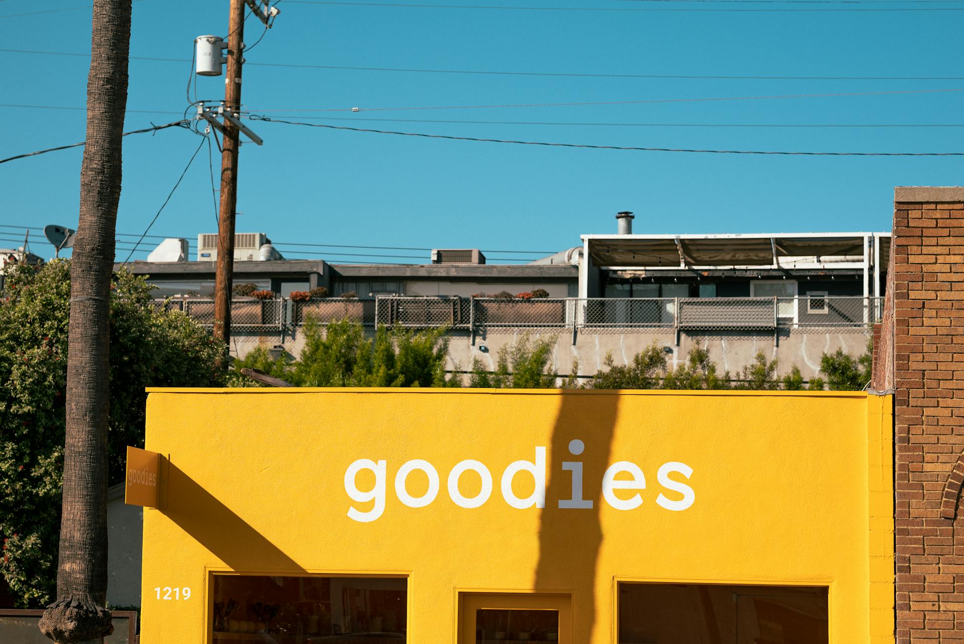 Vibrant yellow storefront with urban backdrop against clear blue sky, perfect for retail concepts.