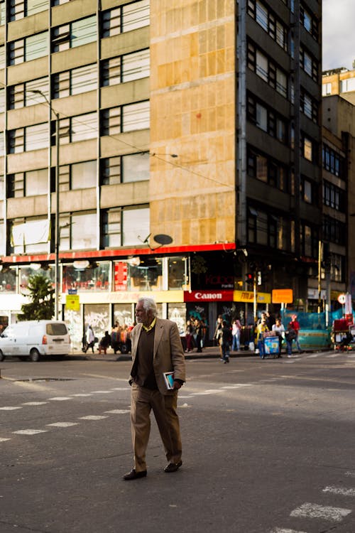 Man in Beige Suit Walking on a Road and Modernist Architecture in Background