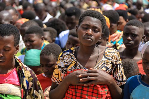 Free A large gathering of people outdoors, praying with closed eyes, conveying unity and spirituality. Stock Photo