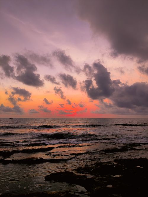 Free Stunning ocean sunset with dramatic clouds and vibrant colors reflecting on the water. Stock Photo