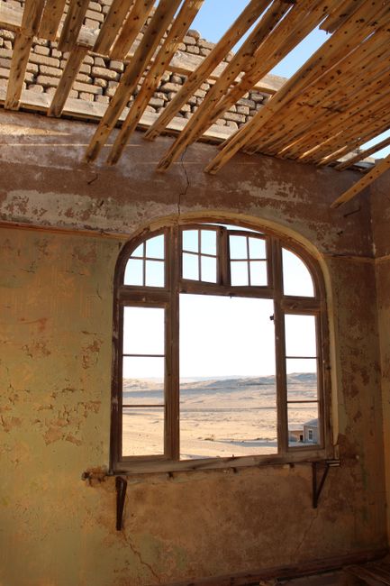 Deserted building interior with decaying walls and a view through a broken window.