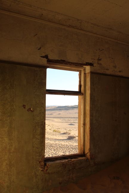 Abandoned room with a window view of a desolate desert landscape.