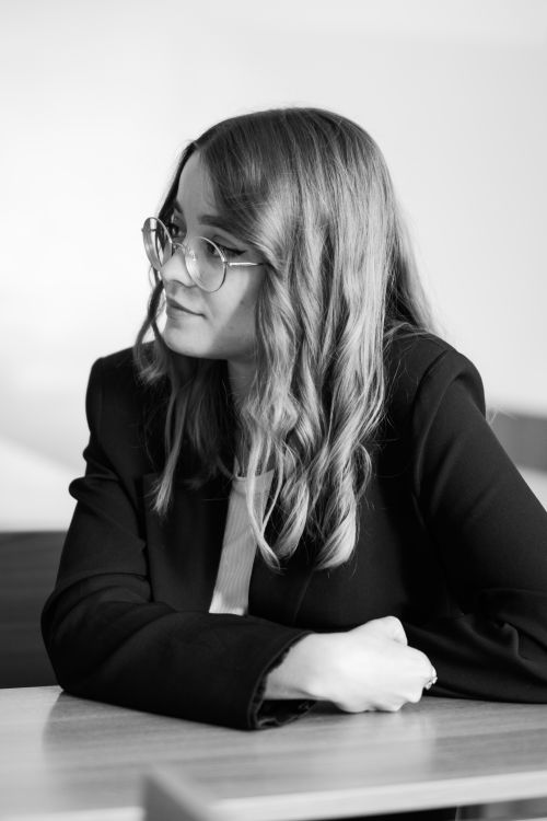 Free Monochrome portrait of a woman with eyeglasses seated at a table, looking sideways. Stock Photo