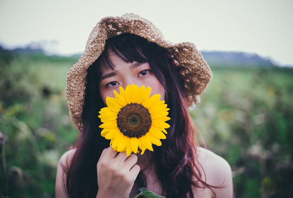 Woman in Brown Sun Hat Holding Sunflower