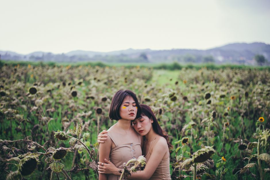 Two young women embrace in a serene sunflower field in Lục Ngạn, Vietnam.