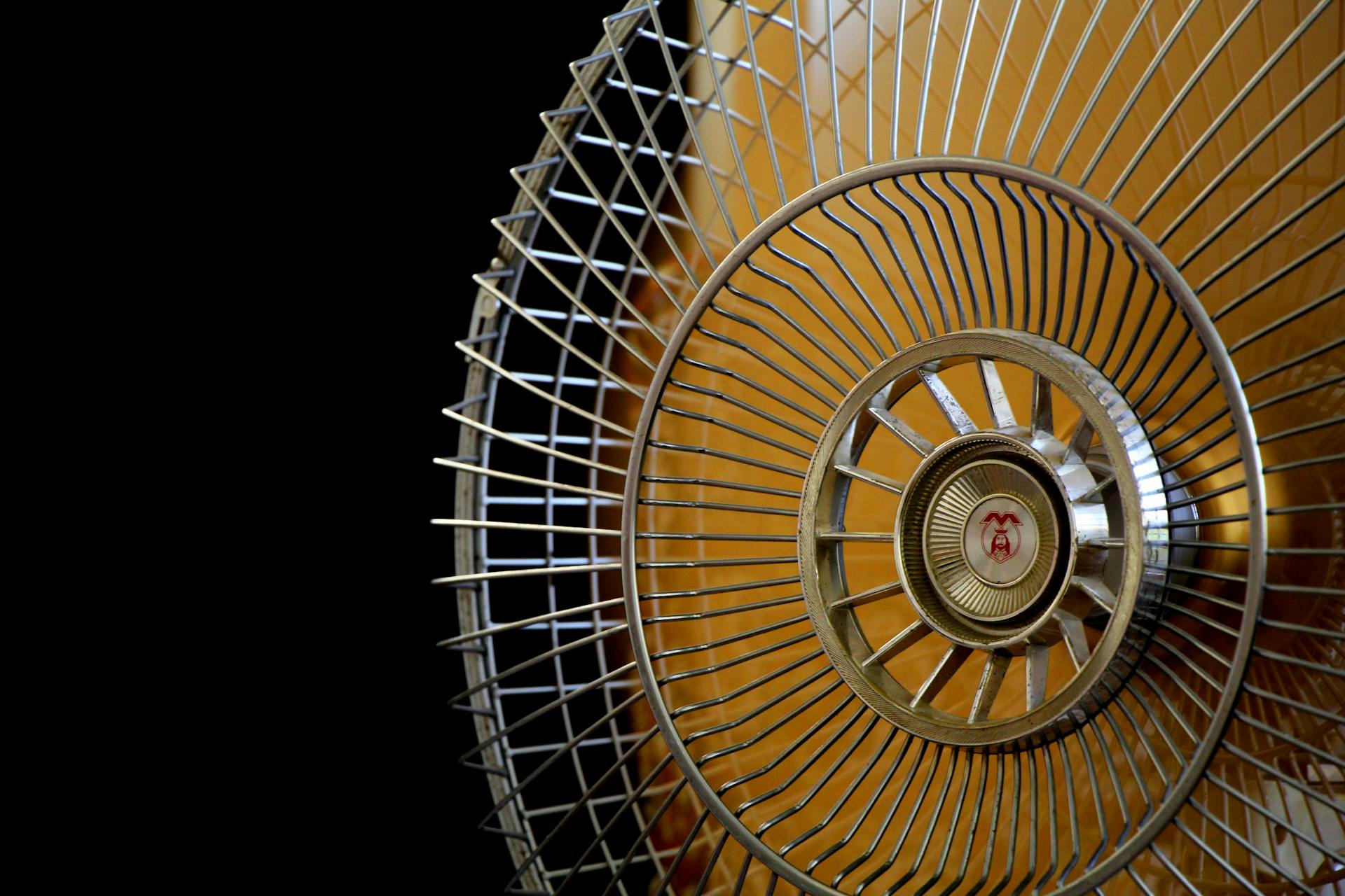 Close-up Photography of Gray Stainless Steel Fan Turned on Surrounded by Dark  Background