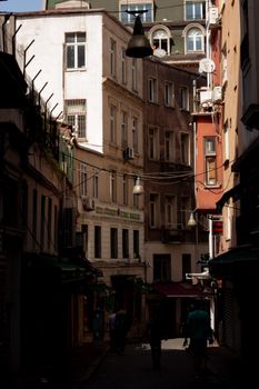 Explore a shadowy narrow alley with historic buildings in Istanbul's vibrant atmosphere.