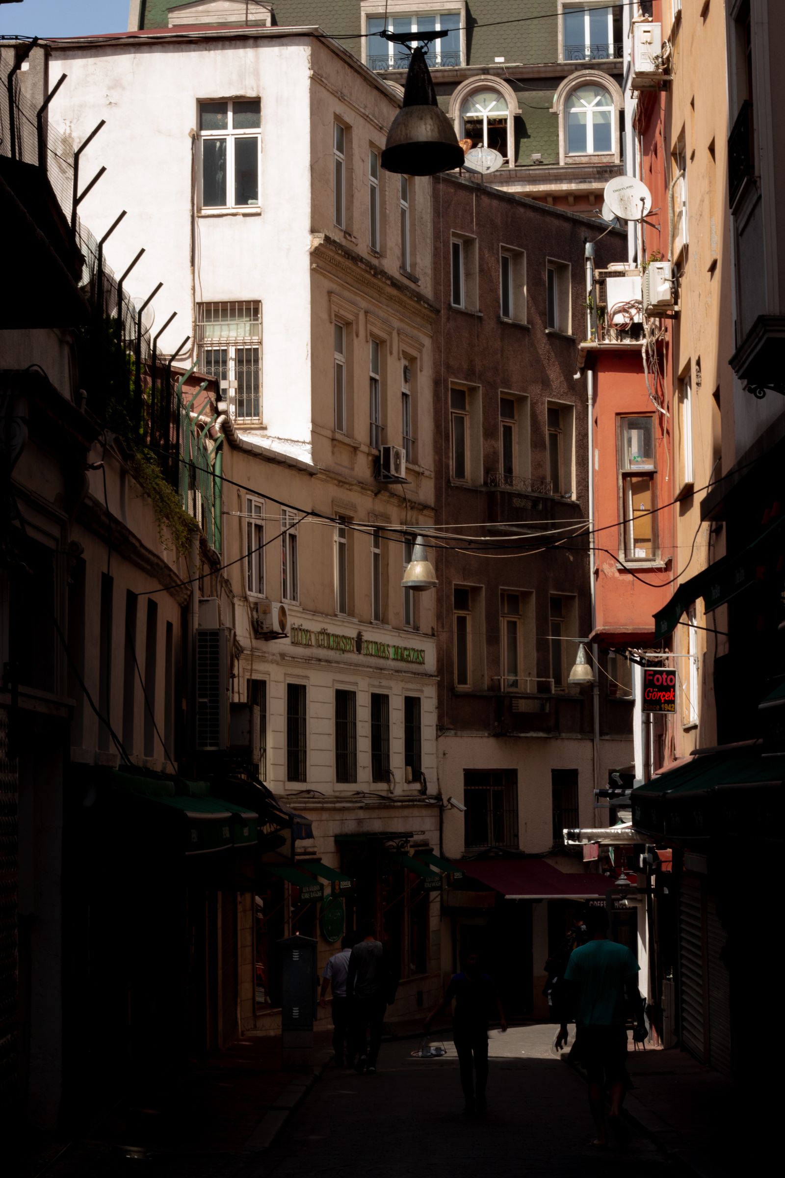 People walking through a shadowed historic street