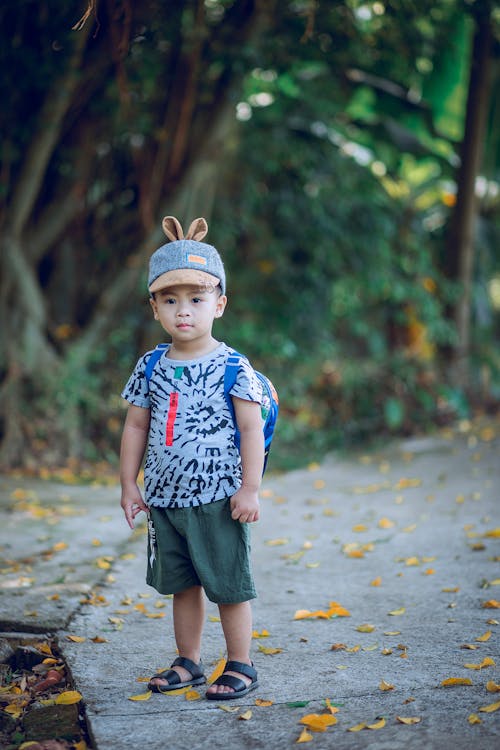 Free Boy Wearing Shirt and Backpack Standing on Concrete Pathway Stock Photo