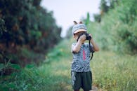 一个年幼的孩子在户外用相机进行创意摄影，捕捉大自然的美丽