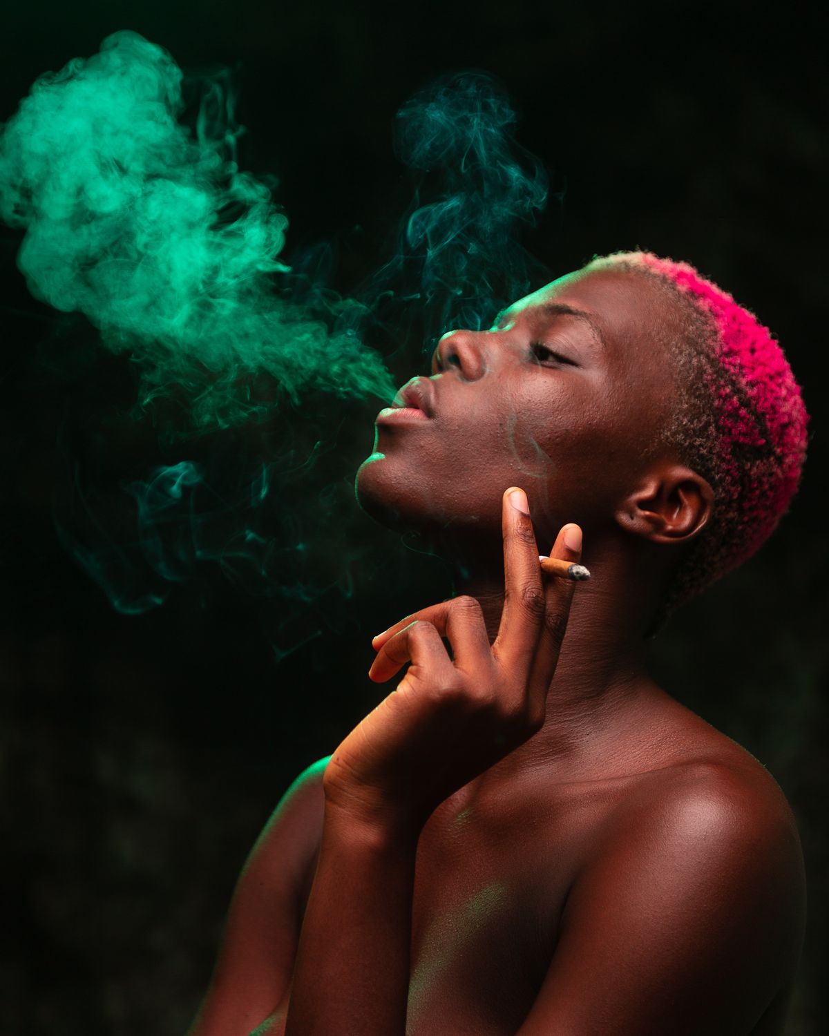 Artistic portrait of a woman with dyed hair and vibrant colored smoke