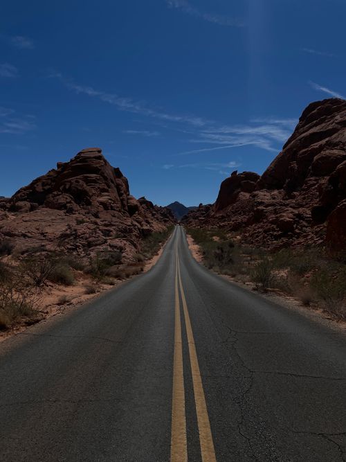 Free A deserted road through stunning rocky desert landscape under clear blue skies. Stock Photo