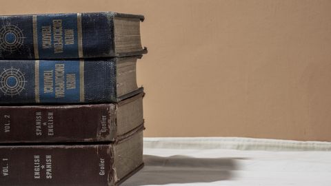 A stack of old encyclopedias and dictionaries with copy space on a neutral background.