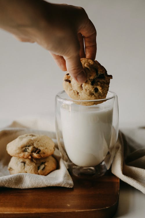 A Person Dipping Cookie to a Glass of Milk