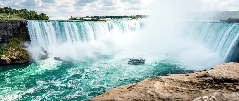 Breathtaking view of Niagara Falls with a sightseeing boat, capturing the grandeur of this iconic landmark. by Ivan Torres