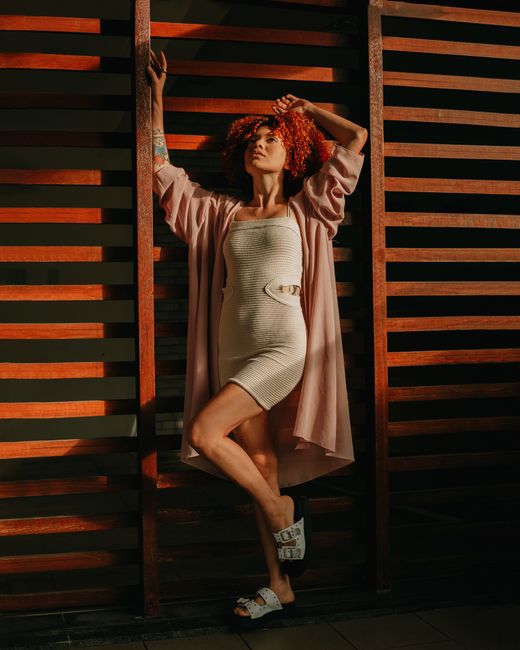 Fashionable woman in summer attire poses against a wooden backdrop in Salvador, Brazil.