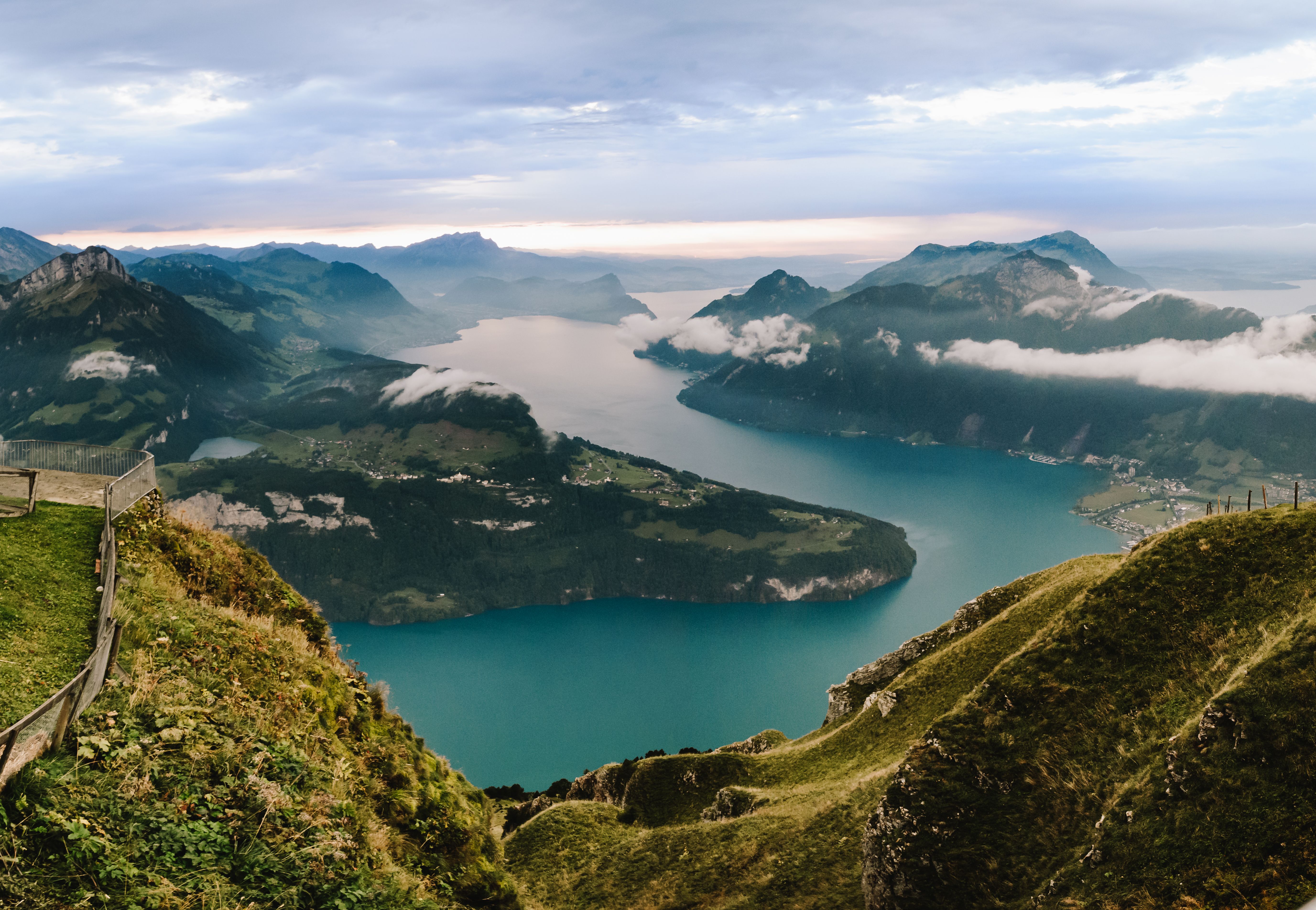 Stunning aerial landscape of a Swiss lake surrounded by majestic mountains under a cloudy sky.
