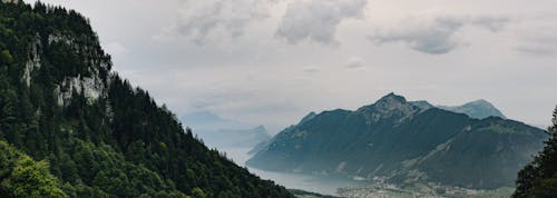 Green Trees on Mountains Under Cloudy Sky