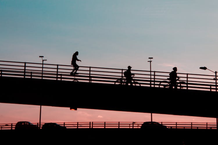 Photo Of Silhouettes Of People Riding Bikes On A Bridge