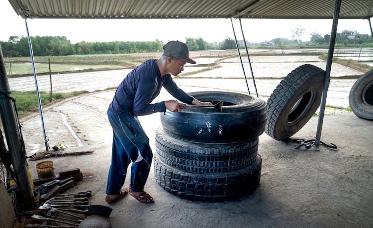 Man In Blue Long Sleeve Shirt Fixing A Tire