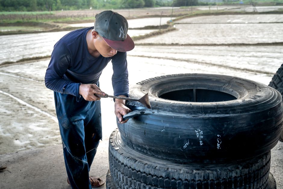 A man working on tire repair outdoors, showcasing craftsmanship and rural life.