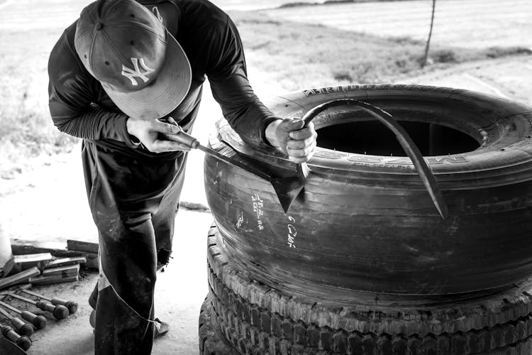 A Man In Black Long Sleeve Shirt Fixing A Tire