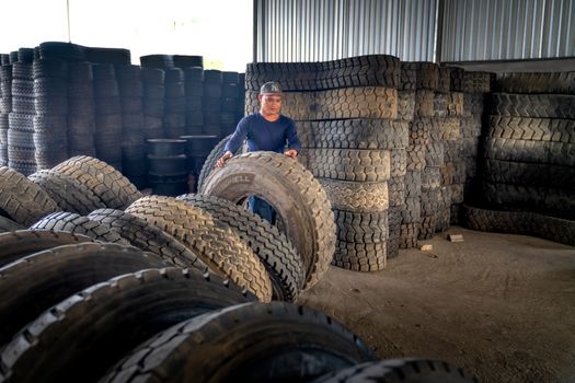 Man organizing large industrial tires in a warehouse, showcasing labor and storage setup.