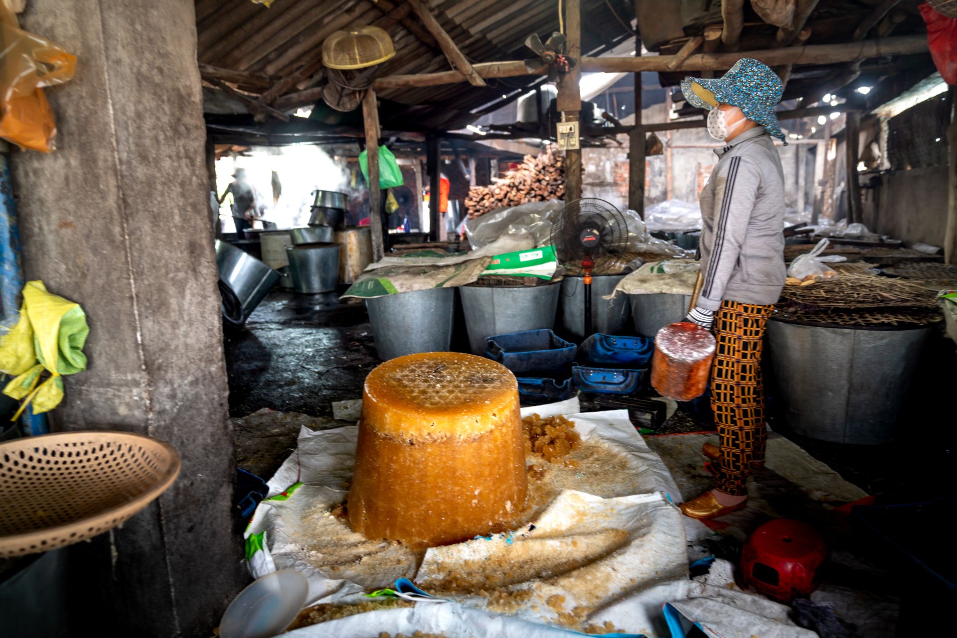 Woman in a village market producing traditional sugar indoors.