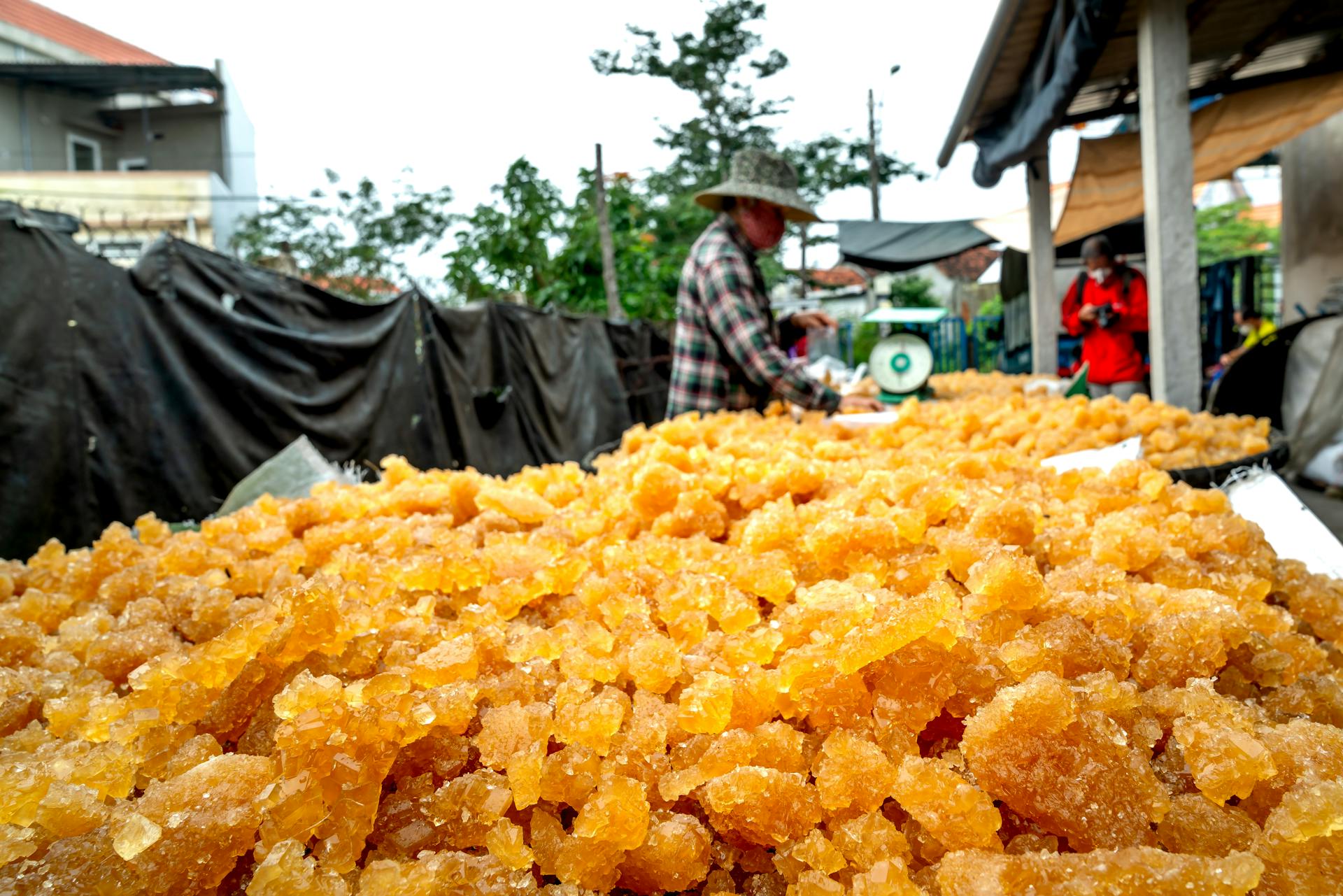 Asian vendor selling crystalline goods at an outdoor market stall.